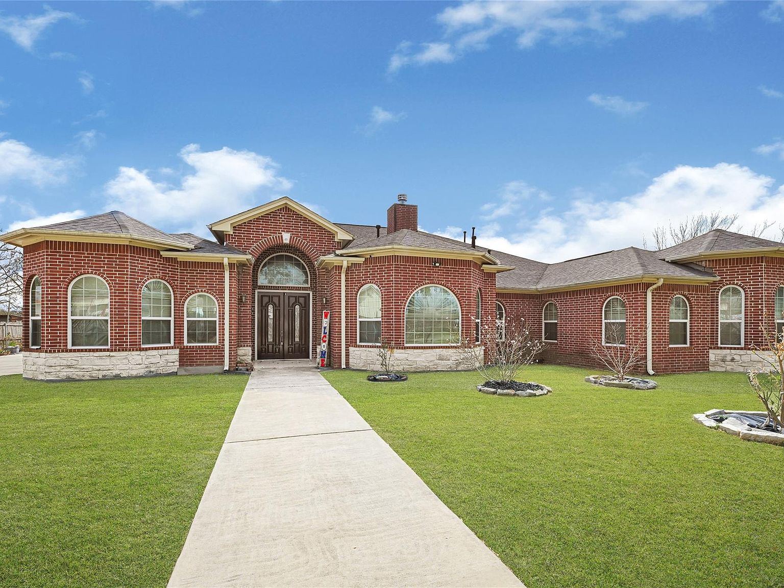 Straight-on front elevation of 6519 Breen Dr showing the arched windows, central entry, and walkway approach to the brick facade